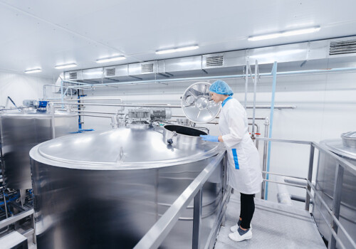 Dairy production, operator woman engineer checks temperature of steel tank with milk. Industrial worker concept. Industrial coatings company canada
